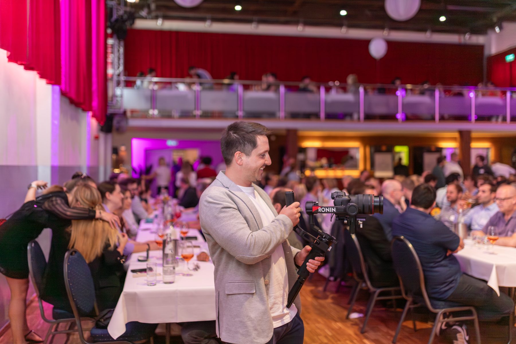 Videograf mit Gimbal-Kamera bei einer Firmenfeier in einer festlich beleuchteten Eventhalle